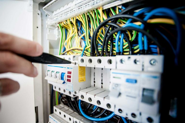 Electrical fuse box with hand holding a screw driver