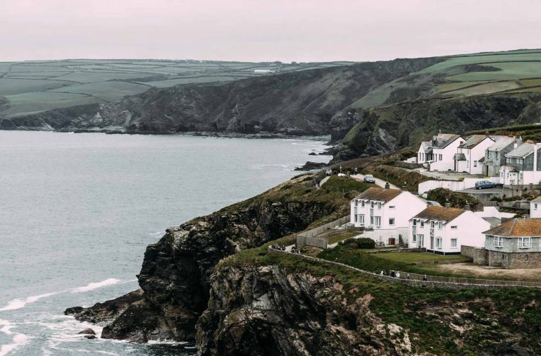 Cornish coastline on cloudy day with white houses.